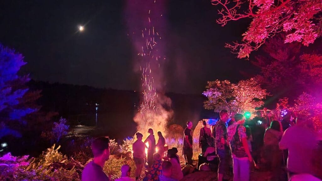 People by a fire under the moon and in red light