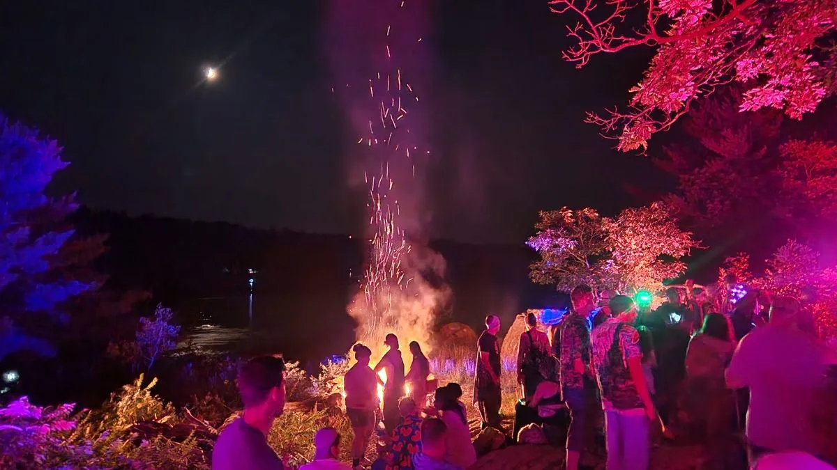 People by a fire under the moon and in red light at Boreal Canoe Trip