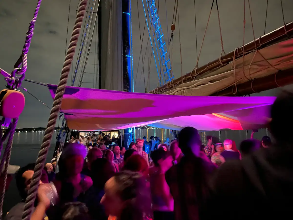 A pink lit crowd of dancers aboard the Kajama tall ship