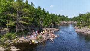 People on rocks by a river and pine forest
