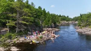 People on rocks by a river and pine forest