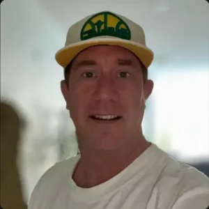 Man DJing in red light, wearing a cap