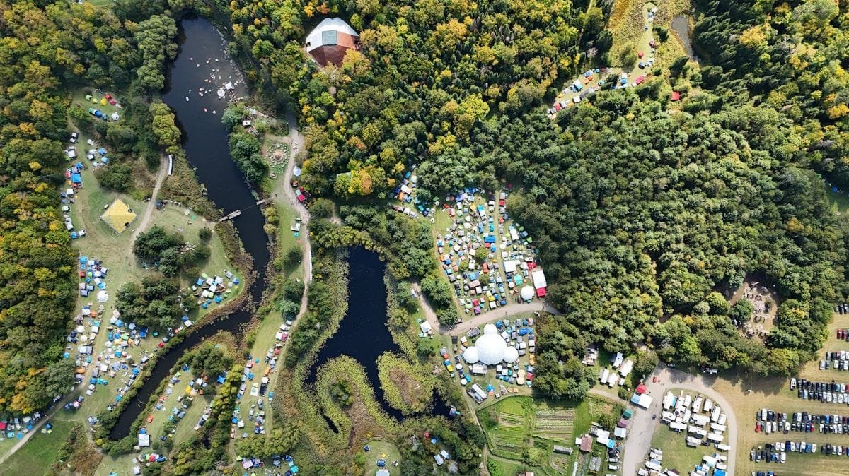 Arial of tent filled fields, stages, ponds and cars.