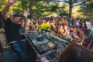 DJ and crowd outside dancing with hands in the air