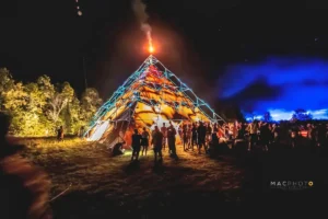 Yellow pyramid with fire shooting from the top and people talking around