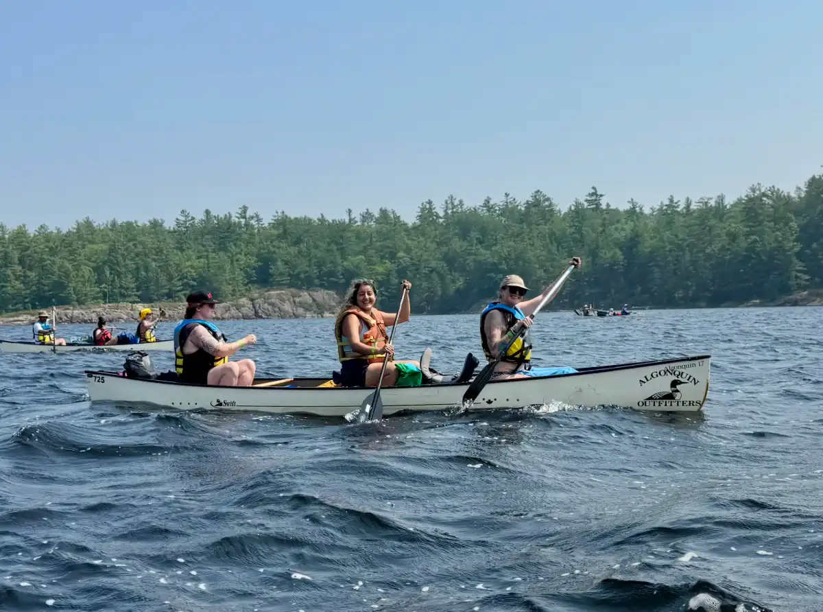 Three in a canoe paddling in windy lake