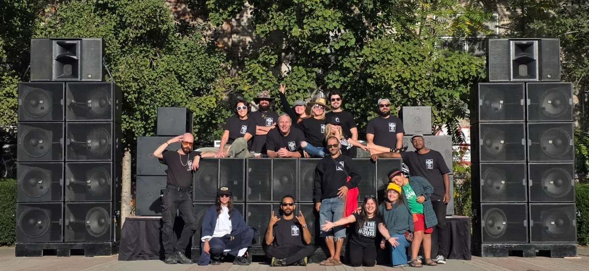 Production crew and large sound system setup in a park