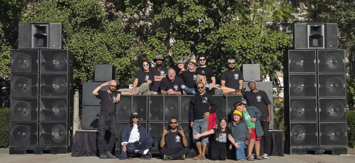 People sitting on and around a large group of speakers