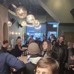 A crowded bar with light balls and curved arches