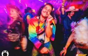 A smiling man with rainbow coloured clothes