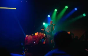 A fidler lit by green lights on stage