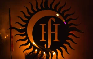 Abstract metal sun behind a moon with Hf letters inside the moon.