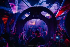 A giant sculpture with a circle and eyes open showing a dancing crowd beyond