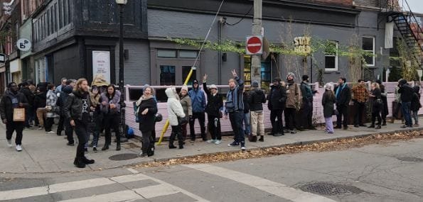 Sidewalk with a lineup of people going around a building