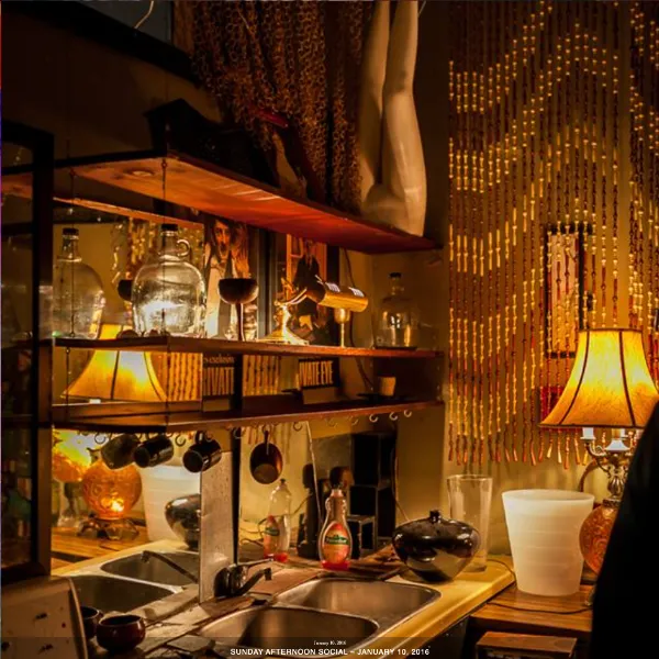 Amber lit interior of a kitchen sink with dishes on shelves above