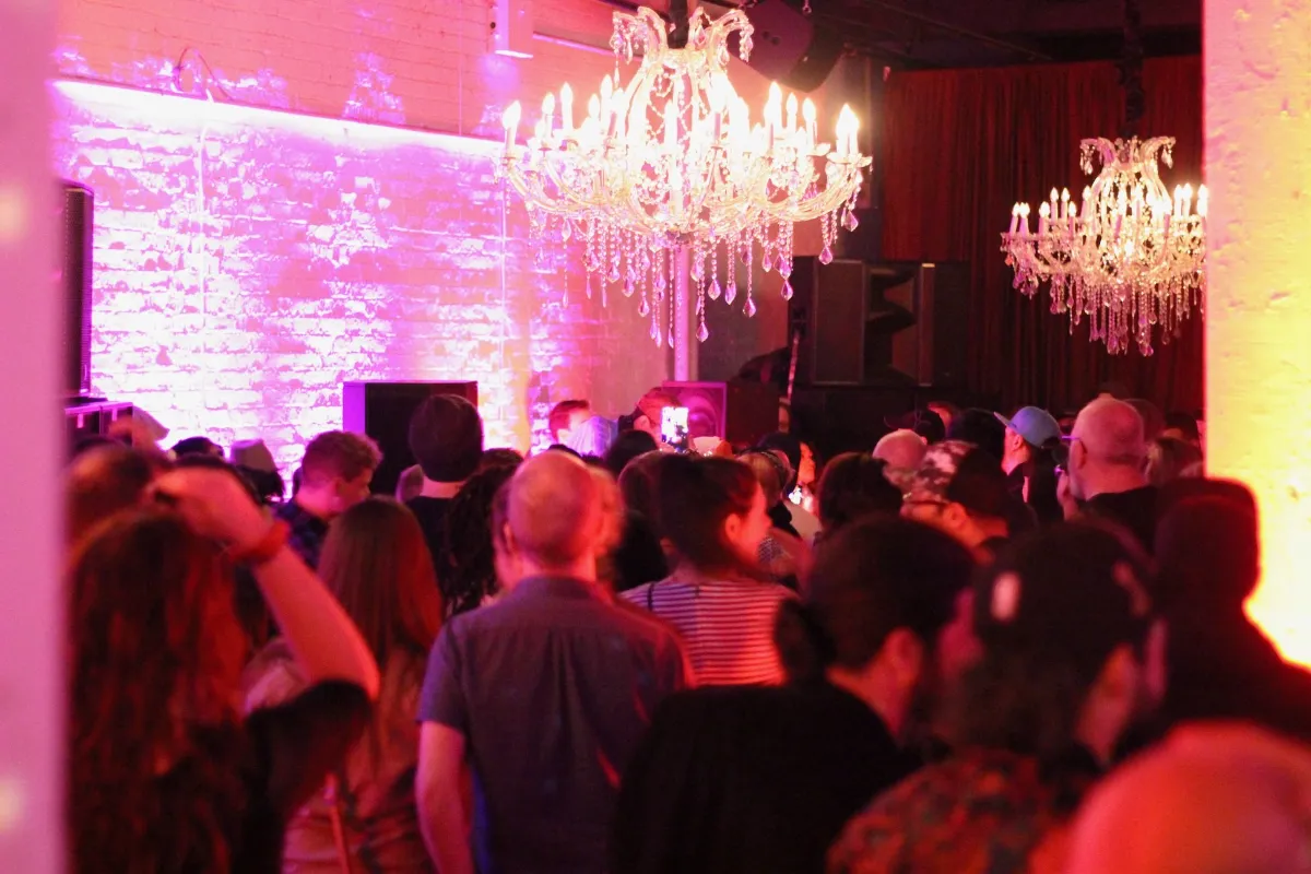 A crowded red lit room of dancers