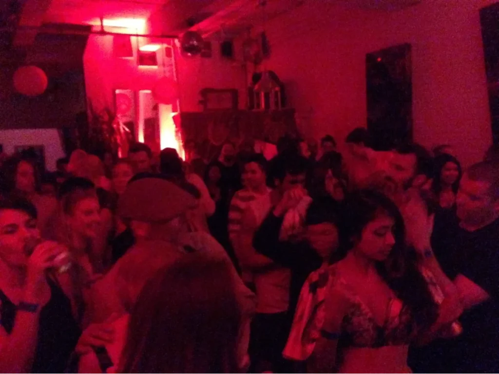 A crowded red lit room of dancers