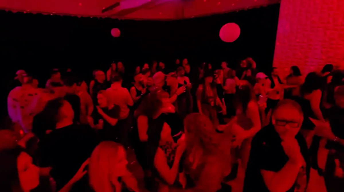 Red lit room with dancing crowd