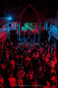 A dancing crowd from above lit red in former church, 2022