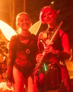Two fairies, one with flute, by fire light