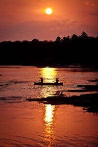 Sunsets over couple in canoe