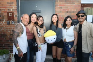Group of friends at a brick building, one holding a plush toy