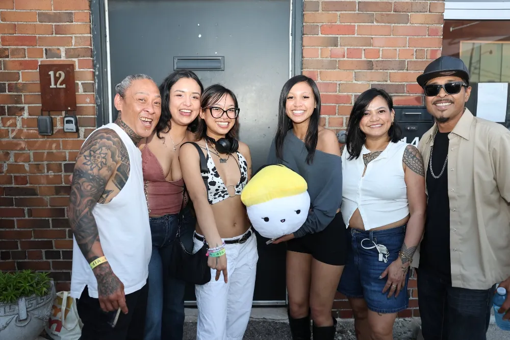 Group of friends at a brick building, one holding a plush toy