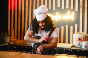 Chef DJ with curly hair and sunglasses plays music at a party.