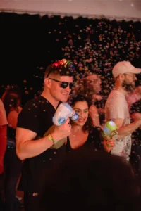 Couple enjoying a bubble party with bubble guns at night