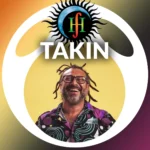 Takin, a man with dreadlocks and glasses, smiles broadly in a colourful shirt.
