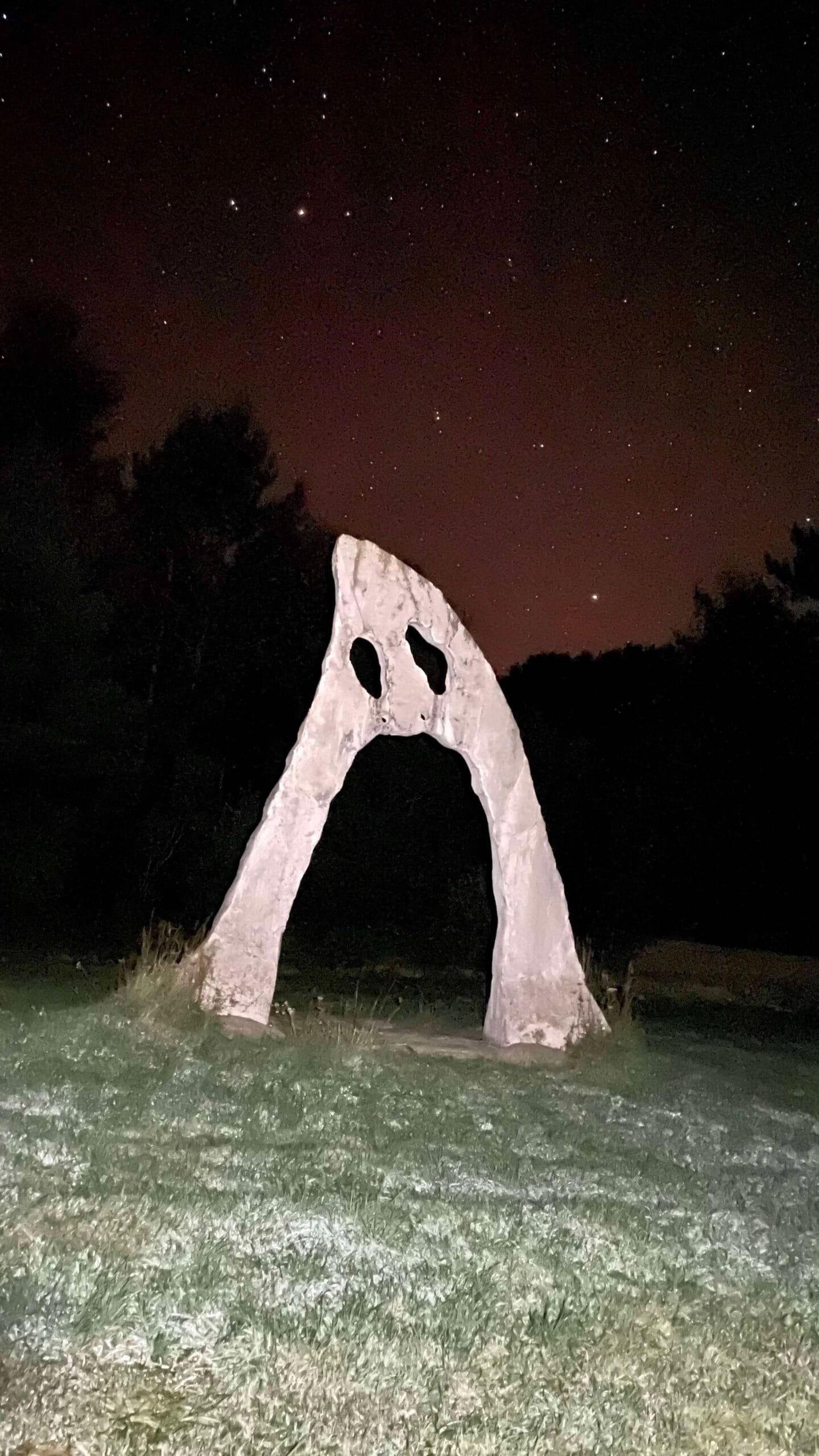 Stone archway with eyes under starry Perseid meteor shower sky