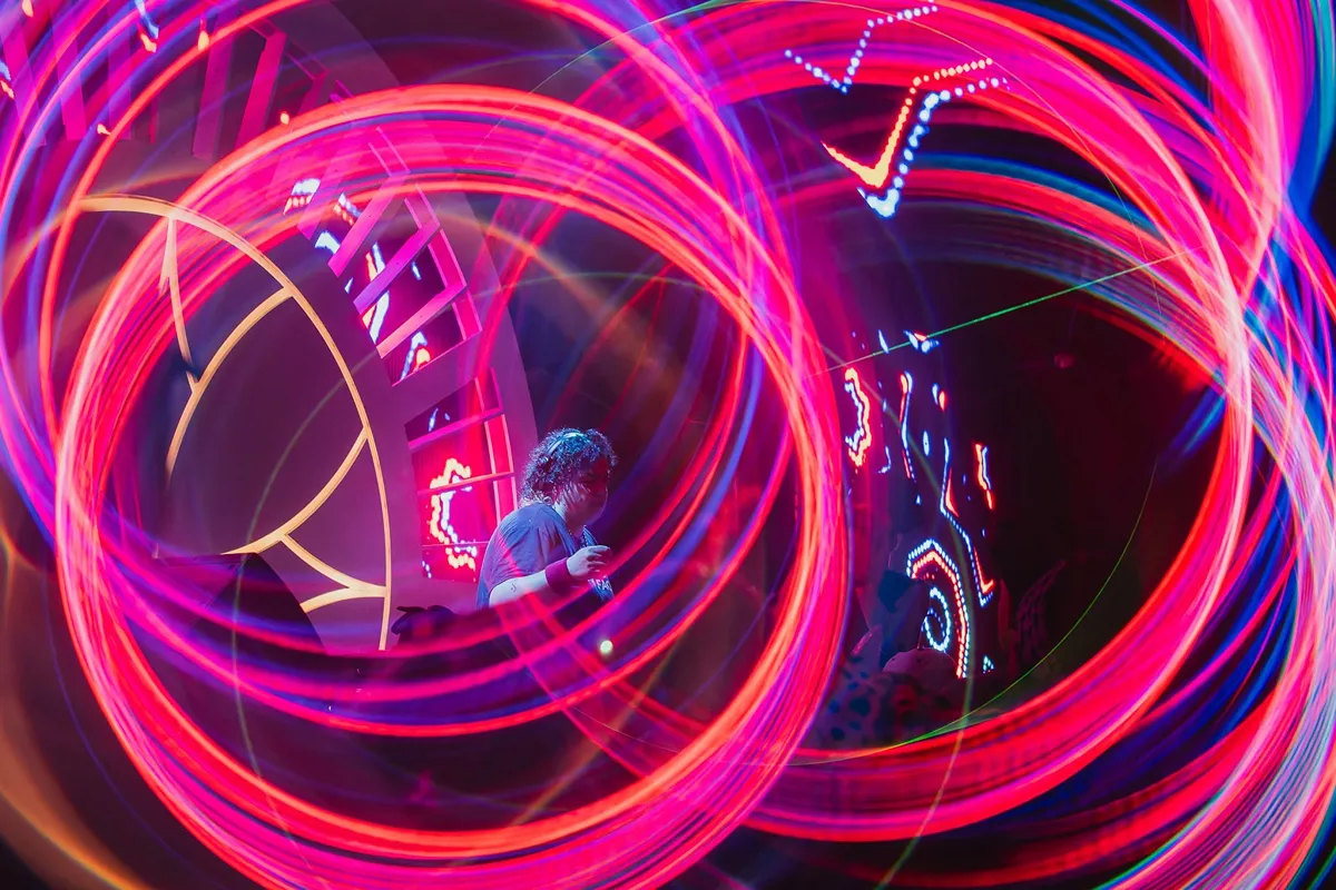 Person enjoying vibrant light trails at a festival event