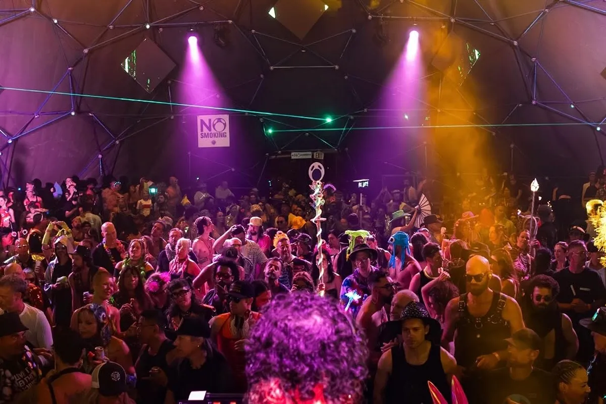 Crowd dancing under colorful lights at outdoor music festival